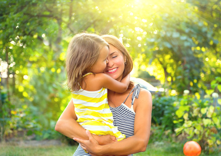 Beautiful mother and her little daughter playing in summer park togetherの写真素材