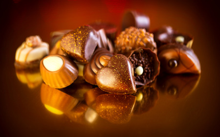Assorted chocolate candies over golden background. Heart shaped chocolateの写真素材