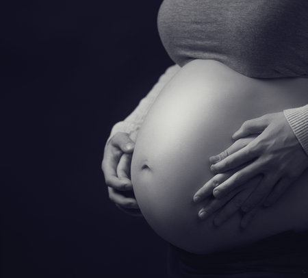 Pregnant woman's belly with hands of mother and father together