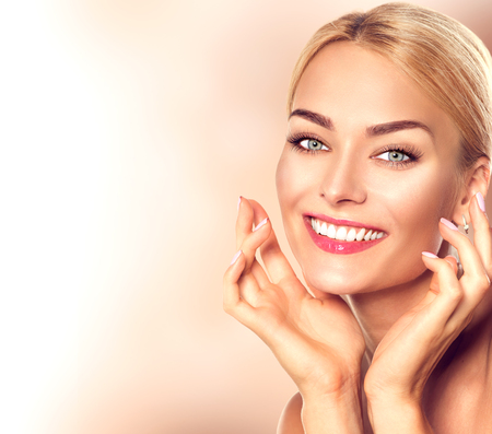 Beauty woman portrait. Beautiful spa girl touching her face and smiling. Perfect fresh skinの写真素材