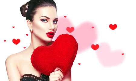 Valentine's Day. Sexy model girl portrait. Gorgeous young brunette woman with heart shaped purple pillow isolated on whiteの写真素材