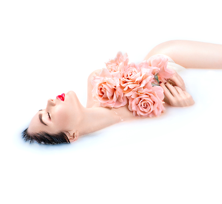 Beauty young model girl with bright makeup and pink roses relaxing in milk bathの写真素材