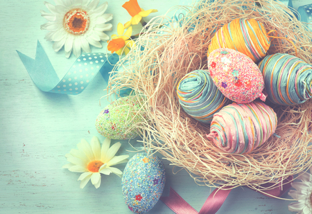 Easter colorful eggs with decorations over blue wooden backgroundの写真素材