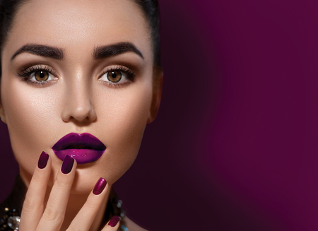 Beauty brunette woman with perfect makeup isolated on burgundy color backgroundの写真素材
