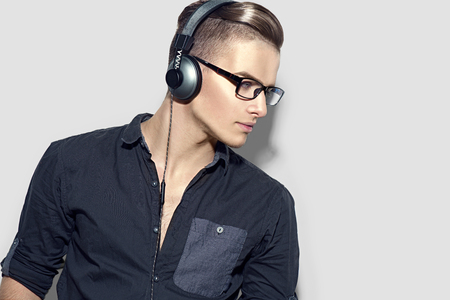 Handsome young man enjoying music on headphones. Model guy in black shirtの写真素材