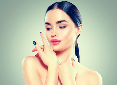 Beauty fashion model woman touching her face. Beautiful sexy brunette girl with luxury makeup and manicureの写真素材