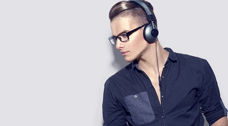 Handsome young man enjoying music on headphones. Model guy in black shirtの写真素材
