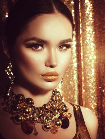 Golden holiday makeup. Golden earrings and necklace. Fashion art hairstyle, manicure and makeupの写真素材