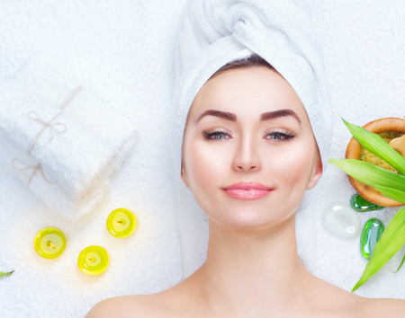 Spa woman applying facial mask. Closeup portrait of beautiful girl with a towel on her head applying facial clay maskの写真素材