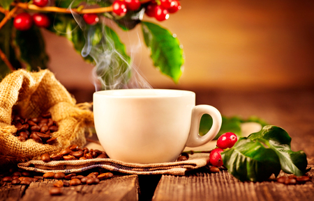 Coffee. Cup of hot steaming coffee closeup and real coffee beans over wooden backgroundの写真素材