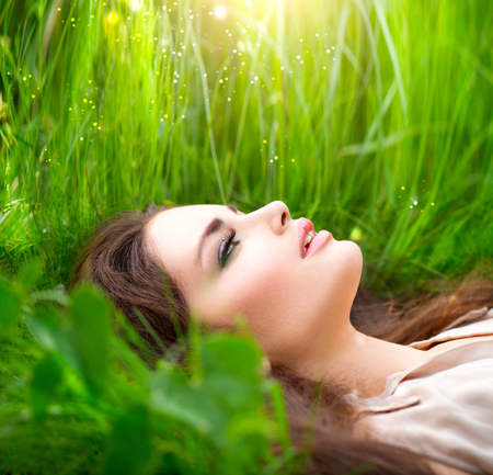 Beauty woman lying on the field in green grass. Enjoying natureの写真素材