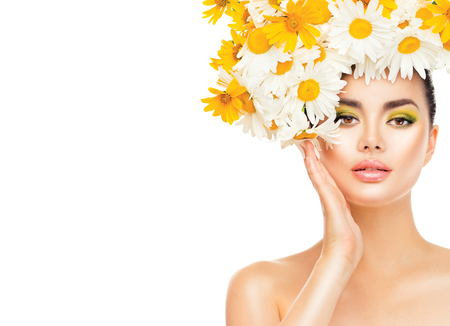 Beauty girl with daisy flowers hairstyle touching her skin. Model woman with blooming chamomile flowersの写真素材