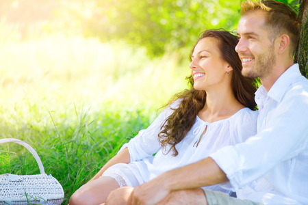 Picnic. Beautiful young couple having romantic dinner outdoorsの写真素材