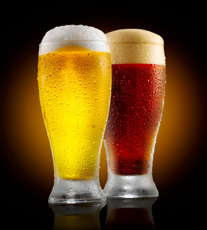 Craft beer. Two glasses of cold light and dark beer isolated on black backgroundの写真素材