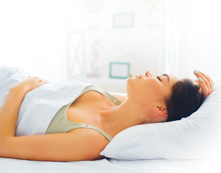 Beauty brunette girl sleeping in her comfortable bedの写真素材