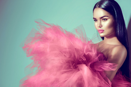 Gorgeous brunette model woman in pink dress posing in studioの写真素材
