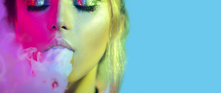 Fashion art portrait of beauty model woman in bright lights with colorful smoke. Smoking girlの写真素材