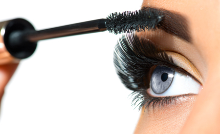 Long lashes closeup. Beautiful woman applying mascara on her eyes. Makeupの写真素材