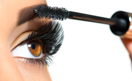 Long lashes closeup. Beautiful woman applying mascara on her eyes. Makeupの写真素材