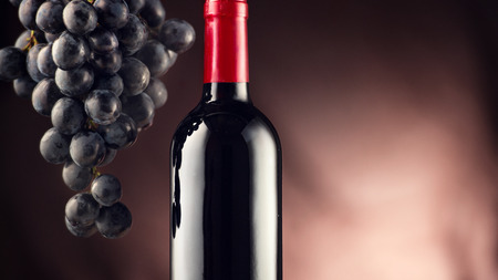 Wine. Bottle of red wine with ripe grapes over black backgroundの写真素材