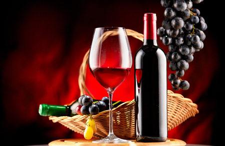 Wine. Bottle and glass of red wine with ripe grapes over black backgroundの写真素材
