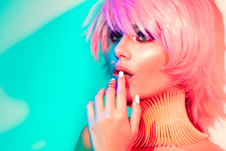 Fashion model woman in colorful bright lights with trendy make-up, manicure and haircutの写真素材