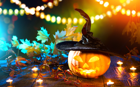 Halloween pumpkin head jack lantern with burning candles over wooden backgroundの写真素材