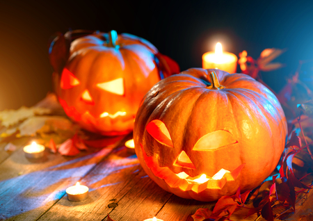 Halloween pumpkin head jack lantern with burning candles over wooden backgroundの写真素材