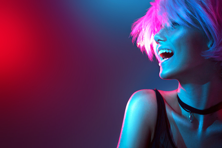 Beauty model girl in colorful bright lights with trendy makeup and haircutの写真素材