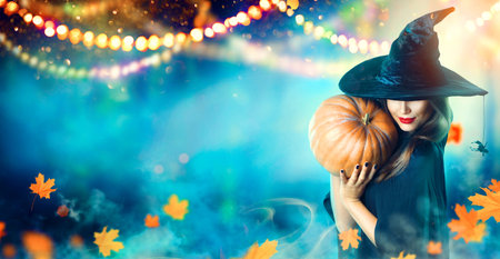 Halloween witch with a carved pumpkin and magic lights in a dark forest