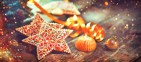 Christmas gingerbread cookies on wooden table decorated with garland and candlesの写真素材