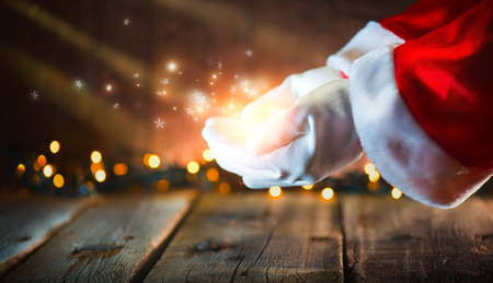 Christmas scene. Santa Claus showing glowing stars and magic dust in open hands. Proposing product