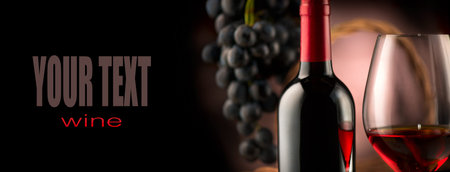 Wine. Bottle and glass of red wine with ripe grapes over black backgroundの写真素材