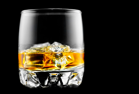 Whisky on the rocks. Glass of whiskey with ice isolated on black backgroundの写真素材