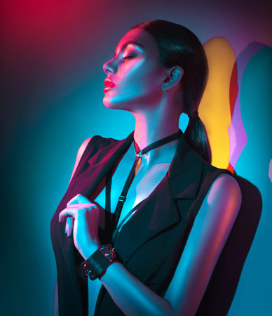 Portrait of sexy young woman in black clothes, fashion accessories, bright makeup in neon lightの写真素材