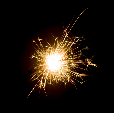Bright sparks on deep black background closeup. Party holiday sparkler isolated on blackの写真素材