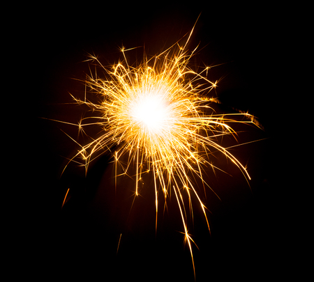 Bright sparks on deep black background closeup. Party holiday sparkler isolated on blackの写真素材