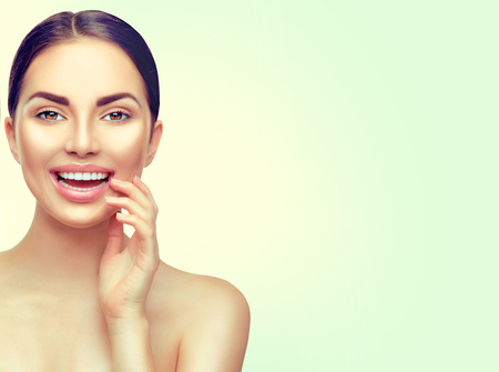 Beauty spa brunette woman touching her face and smiling. Teeth whiteningの写真素材