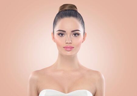 Beauty fashion model girl face on beige background. Professional makeup for brunette with brown eyesの写真素材