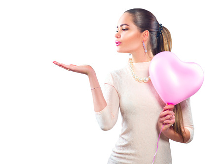 Valentine's day. Beauty girl with pink heart shaped air balloon pointing hand, isolated on white backgroundの写真素材