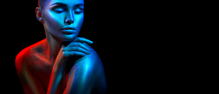 Fashion model woman in colorful bright sparkles and neon lights posing in studio, portrait of beautiful sexy girl. Art design colorful vivid makeupの写真素材