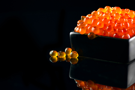Caviar. Salmon caviar in a bowl over black background. Closeup trout caviarの写真素材