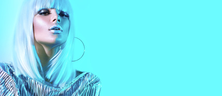 High fashion model girl in colorful bright neon lights posing in studio. Portrait of beautiful sexy woman in white wig and silver trendy glowing makeupの写真素材