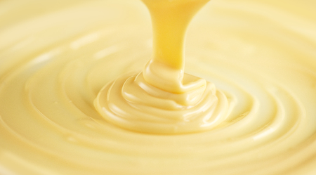 White chocolate. Pouring melted liquid white chocolate. Closeup of molten liquid hot chocolate swirl. Confectioneryの写真素材