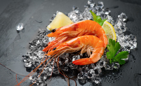 Shrimps. Fresh prawns on a black background. Seafood on crashed ice with herbs. Healthy food, cookingの写真素材