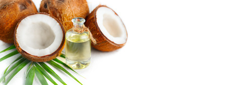 Coconut oil in a bottle with coconuts and green palm tree leaf isolated on a white background. Skincare conceptの写真素材