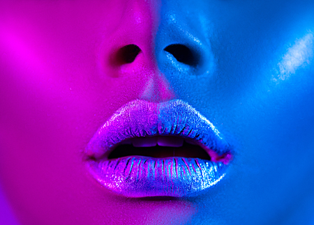 Beautiful sexy girl, trendy glowing makeup, metallic silver lips. High fashion model woman in colorful bright neon lights posing in studioの写真素材