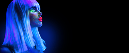 Fashion model woman in neon light. Beautiful model girl with colorful bright fluorescent makeup isolated on black. Ultraviolet, UVの写真素材