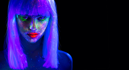 Fashion model woman in neon light. Beautiful model girl with colorful bright fluorescent makeup isolated on black. Ultraviolet, UVの写真素材