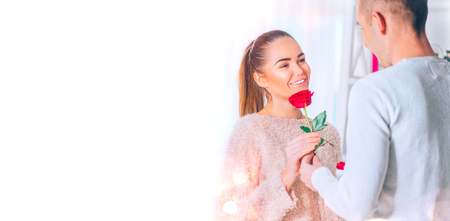 St. Valentine's Day. Love concept. Young man giving a flower and a gift to his girlfriendの写真素材
